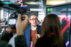 Image of a man facing the camera giving an interview to press people